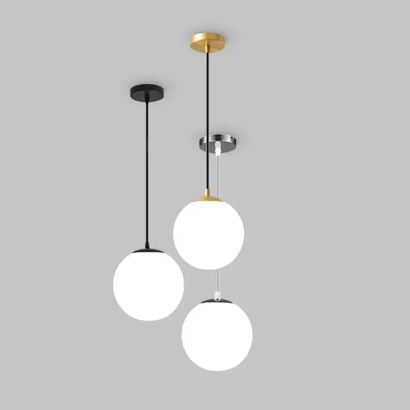 Modern glass globe pendant light with gold finish hanging above a contemporary dining table.