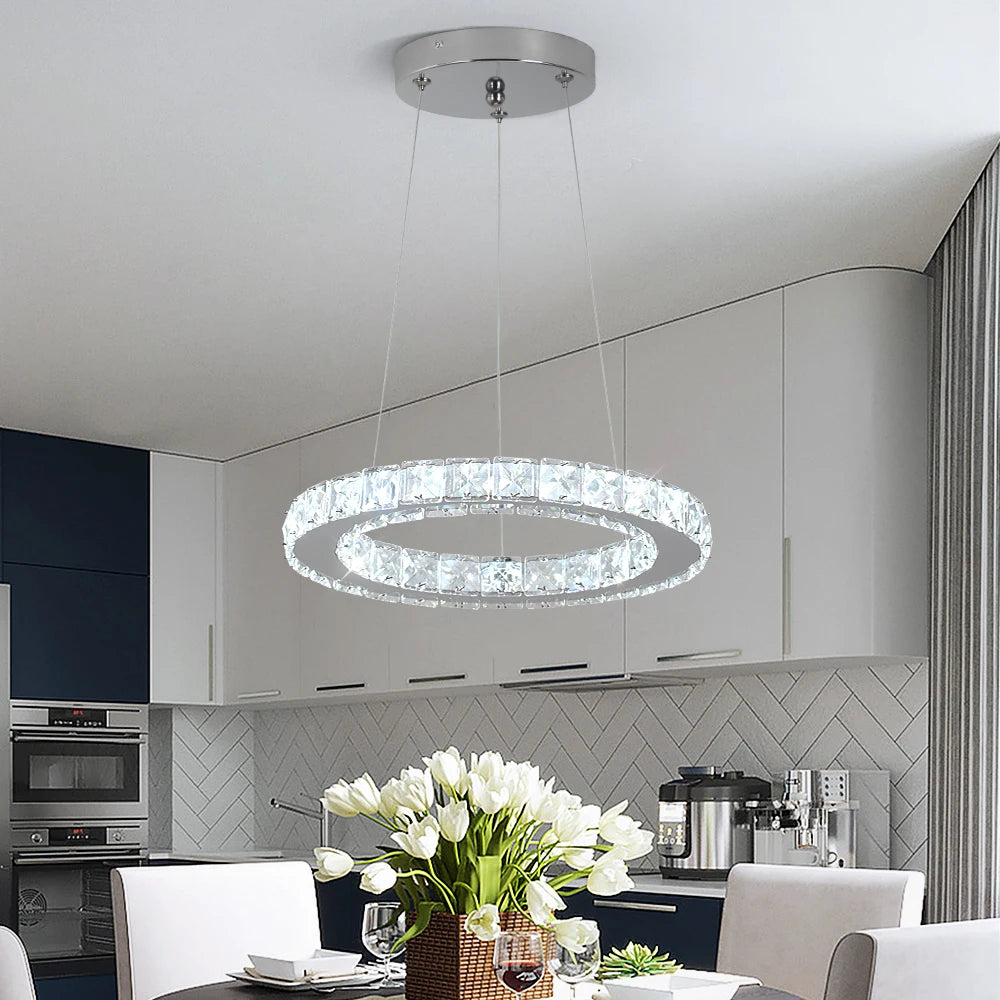 Luxury crystal ring LED chandelier suspended above a modern dining table in an elegant contemporary home.