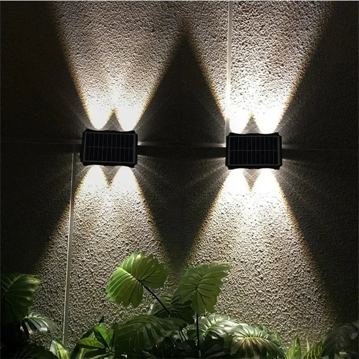 Modern waterproof solar LED wall light installed on an exterior wall illuminating a garden pathway.