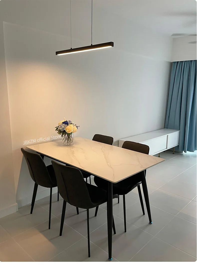 Modern linear LED pendant light suspended above a dining table in a contemporary dining room.