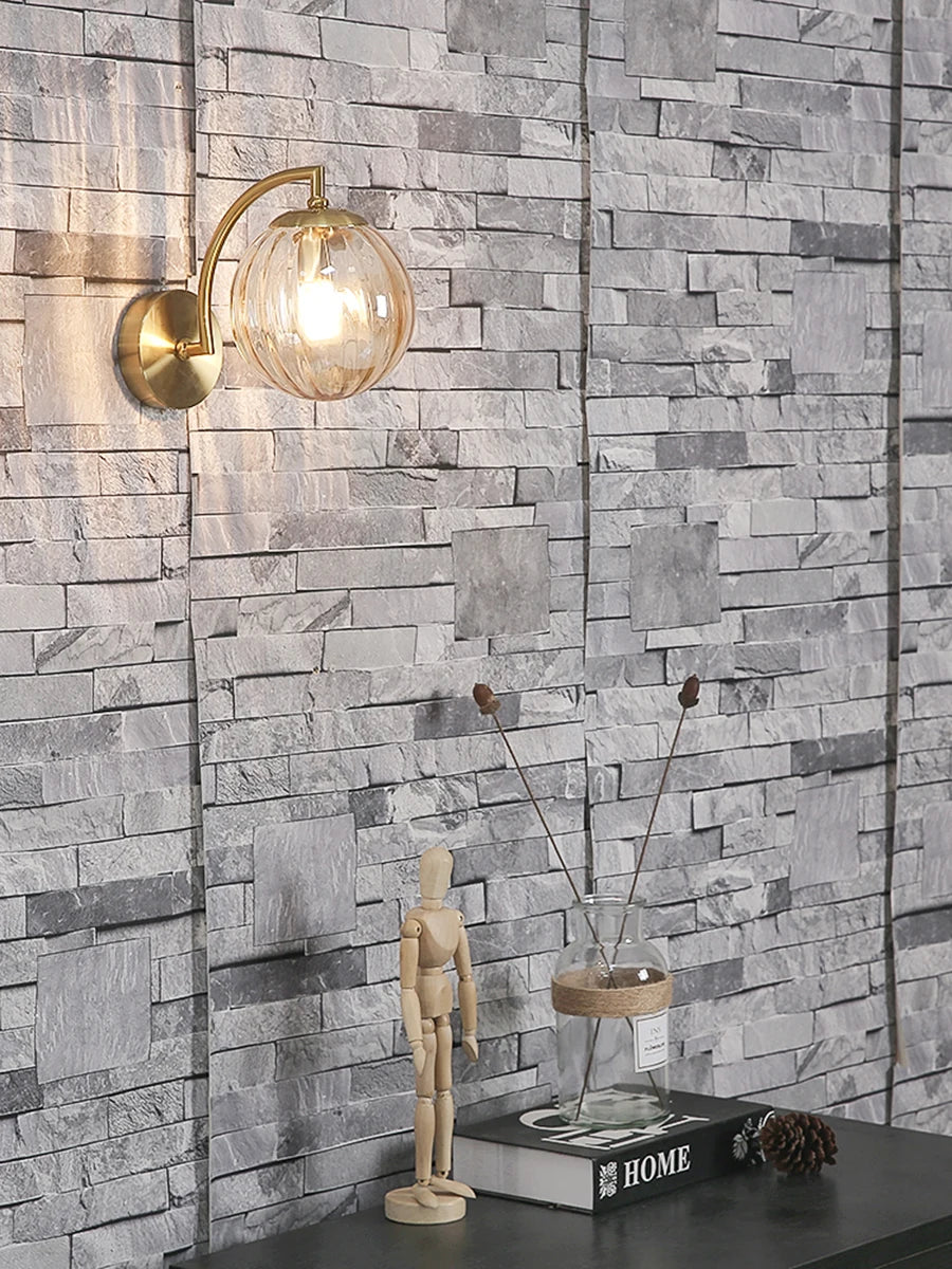 Modern Nordic glass LED wall sconce mounted beside a bed in a contemporary bedroom with warm ambient lighting.