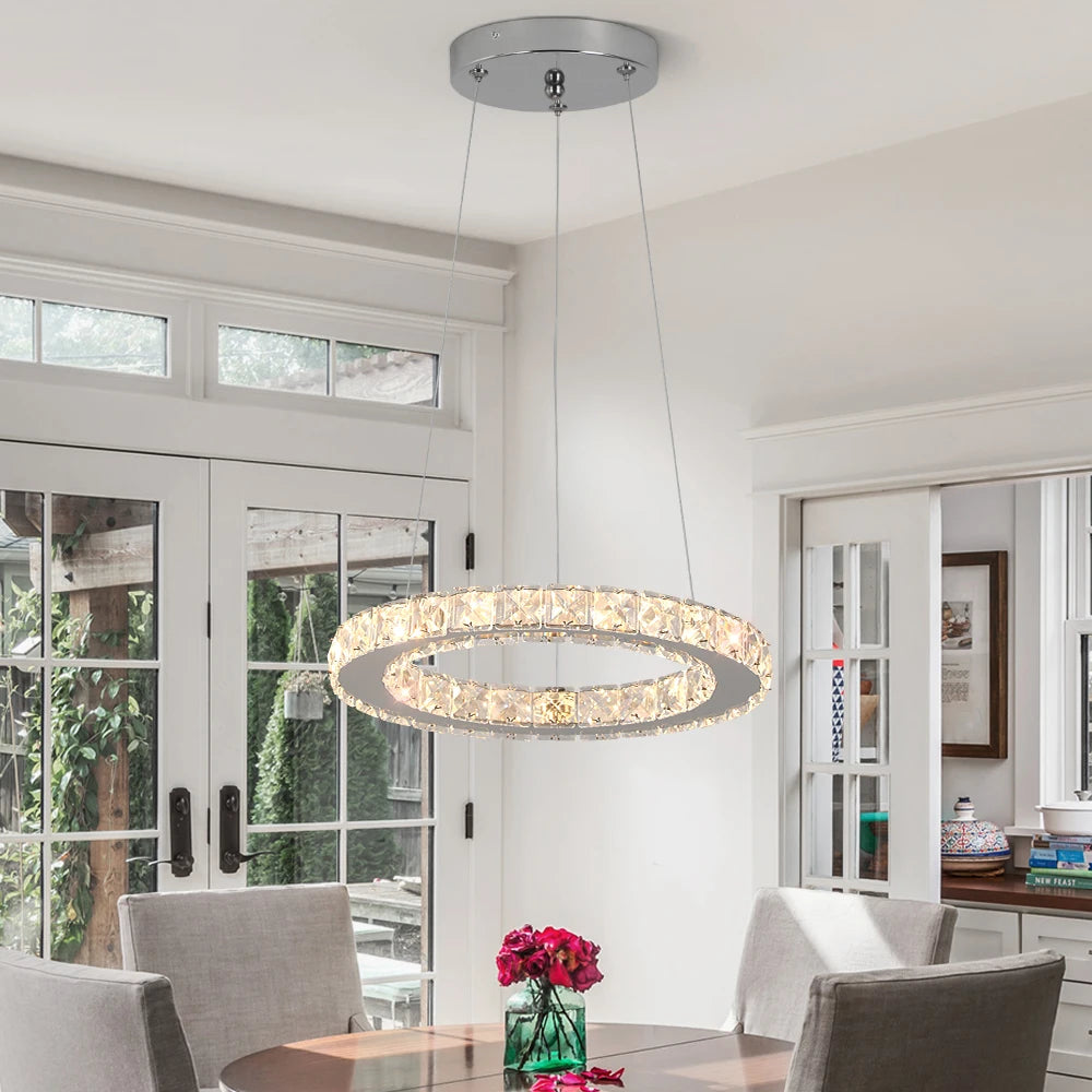 Luxury crystal ring LED chandelier suspended above a modern dining table in an elegant contemporary home.