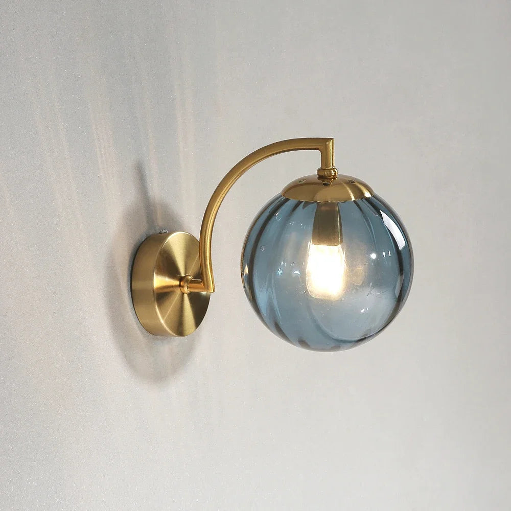 Modern Nordic glass LED wall sconce mounted beside a bed in a contemporary bedroom with warm ambient lighting.