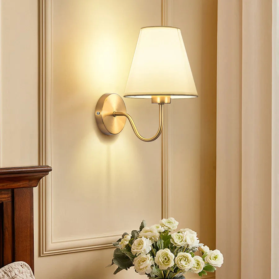 Modern fabric wall sconce installed beside a bed in a contemporary bedroom with warm ambient lighting.