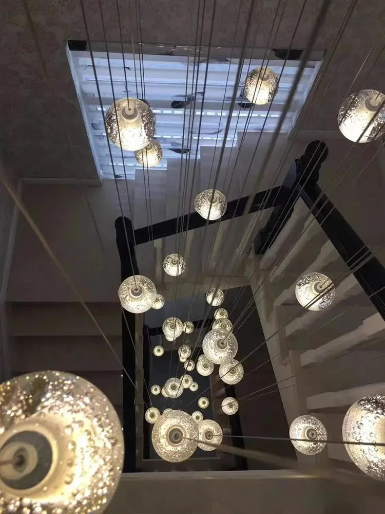 Modern spiral crystal LED chandelier cascading down a luxury staircase in a contemporary home.