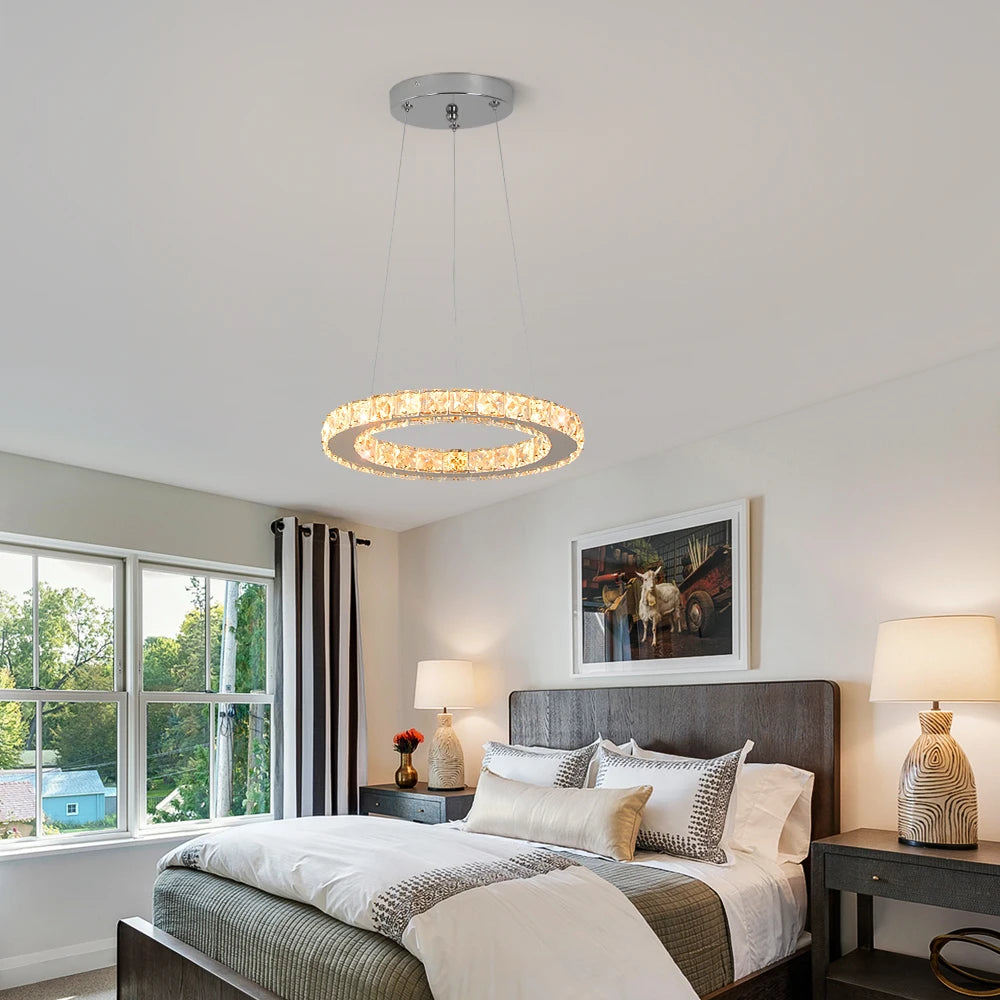 Luxury crystal ring LED chandelier suspended above a modern dining table in an elegant contemporary home.