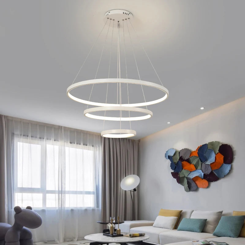 Modern LED ring chandelier suspended above a dining table in a luxury contemporary home.