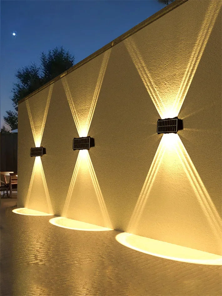Modern waterproof solar LED wall light installed on an exterior wall illuminating a garden pathway.