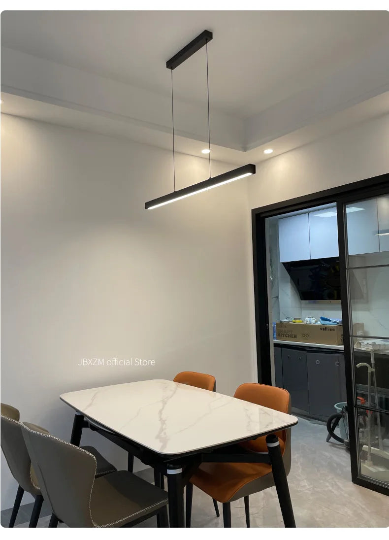 Modern linear LED pendant light suspended above a dining table in a contemporary dining room.
