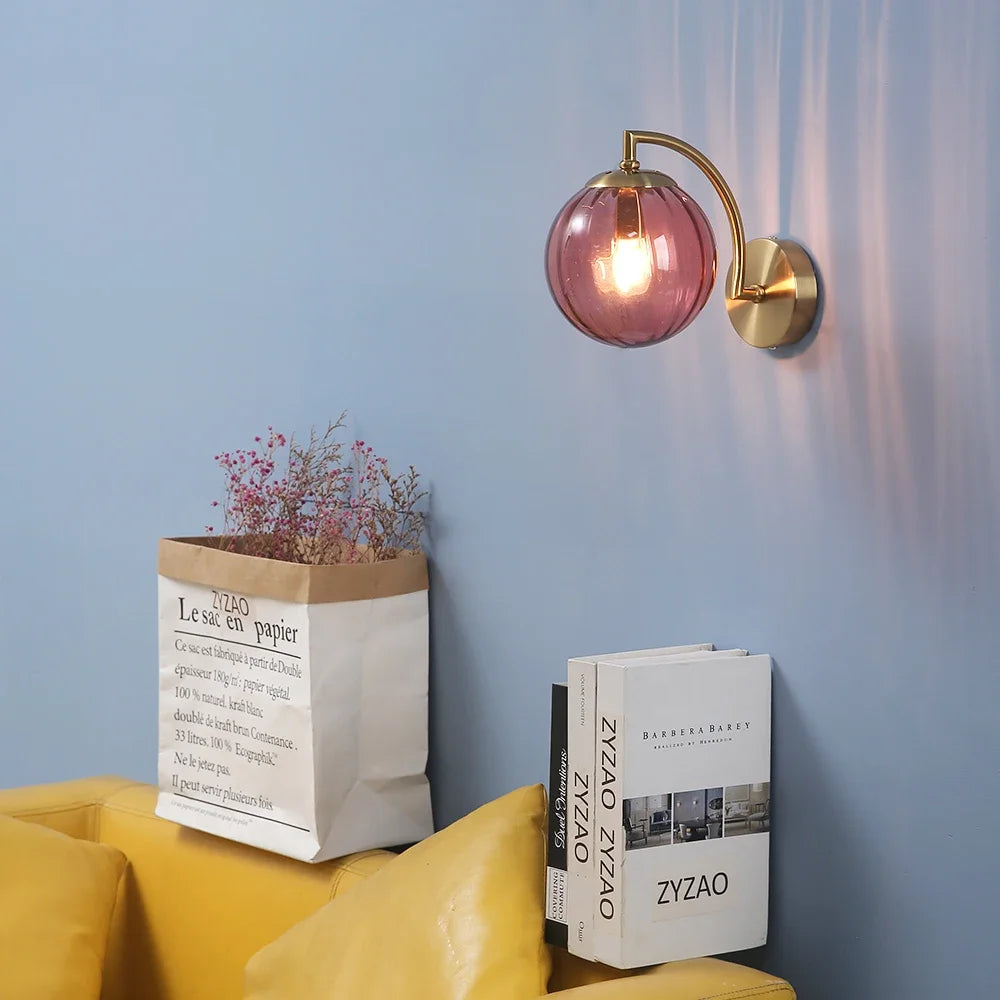 Modern Nordic glass LED wall sconce mounted beside a bed in a contemporary bedroom with warm ambient lighting.