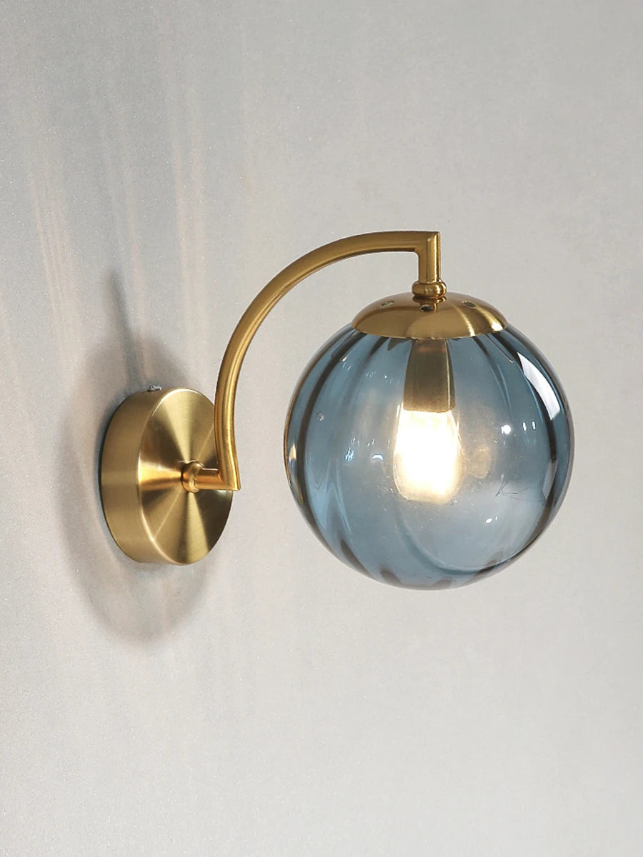 Modern Nordic glass LED wall sconce mounted beside a bed in a contemporary bedroom with warm ambient lighting.
